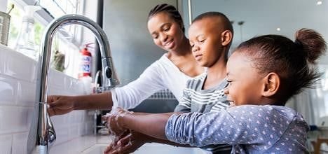 Madre y niños lavándose las manos en el lavaplatos